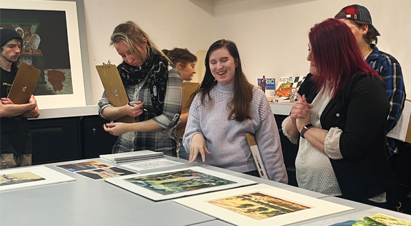 Students view and discuss artworks displayed on study tables at the Beach Museum of Art .